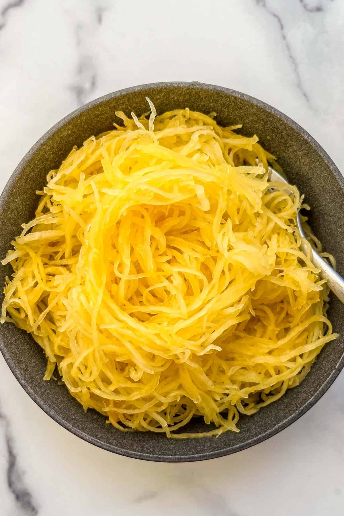 Roasted spaghetti squash noodles in a black bowl.