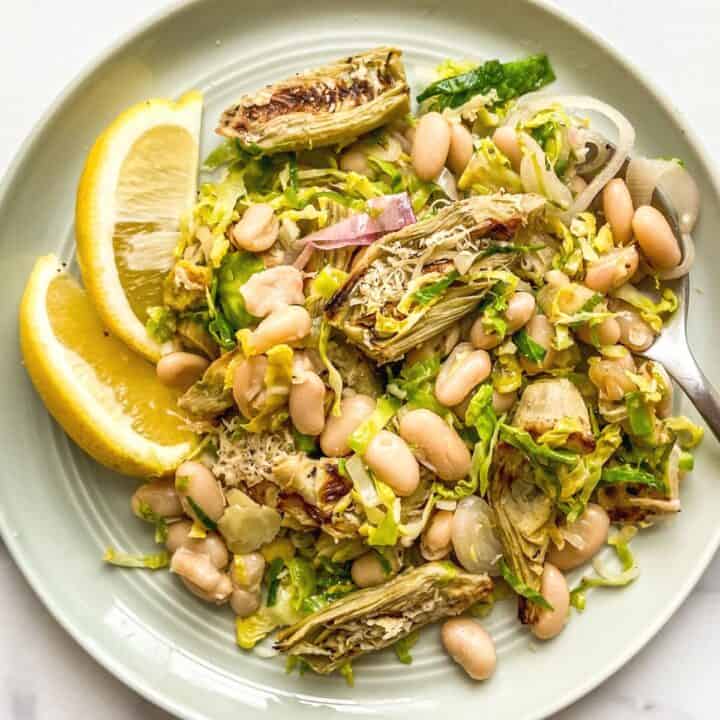 An artichoke and white bean salad on a small green plate.