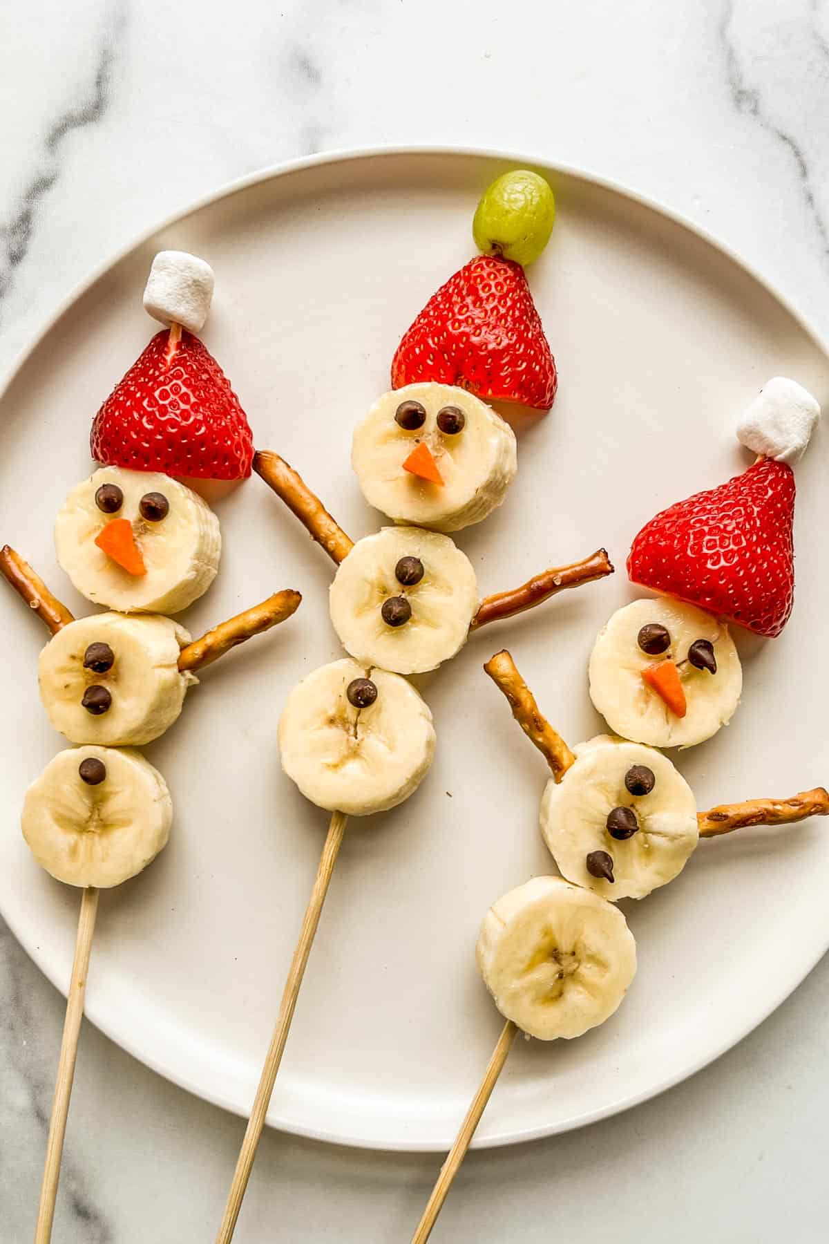 Three banana snowmen on a white plate.