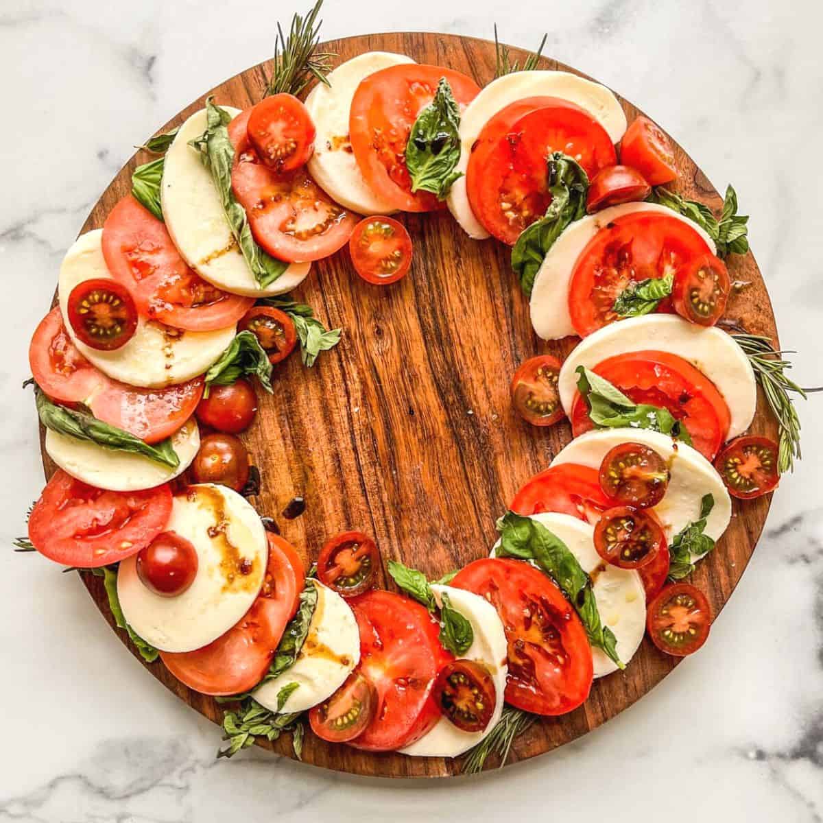 A caprese wreath on a wood plate.
