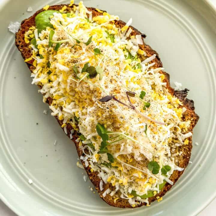 A piece of grated egg avocado toast on a small green plate.