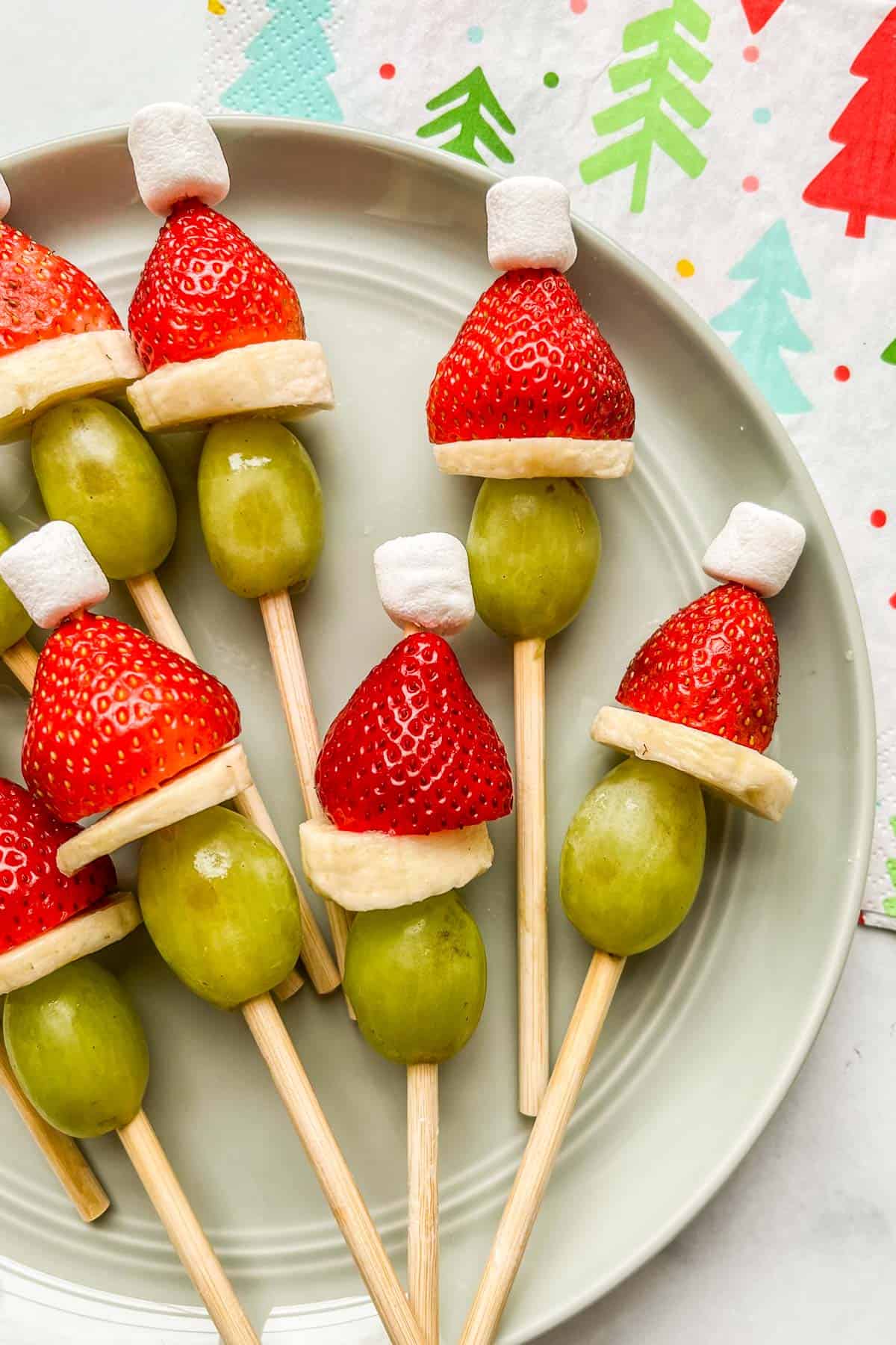 Grinch fruit skewers on a light green plate.