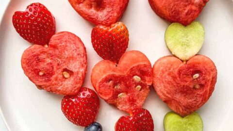 Heart fruit skewers on a white plate.