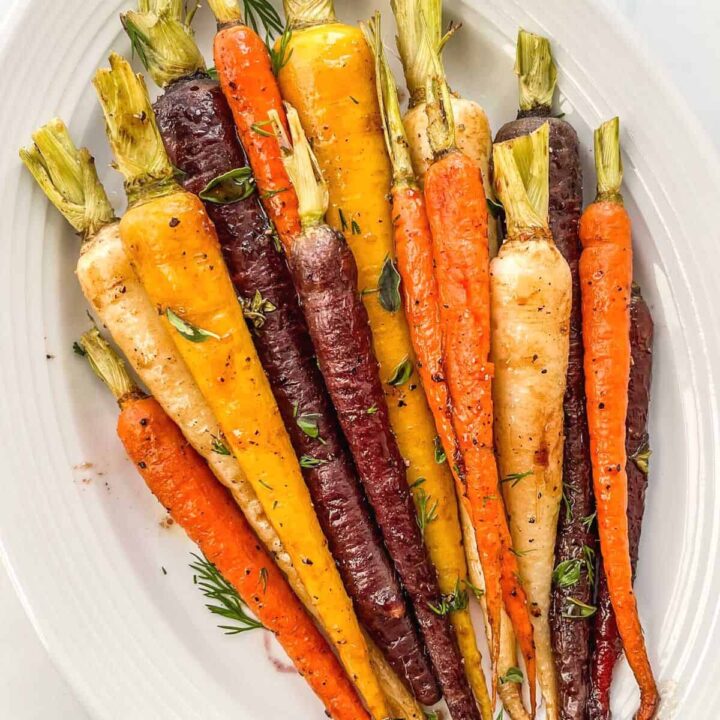 Roasted rainbow carrots on a white serving plate.