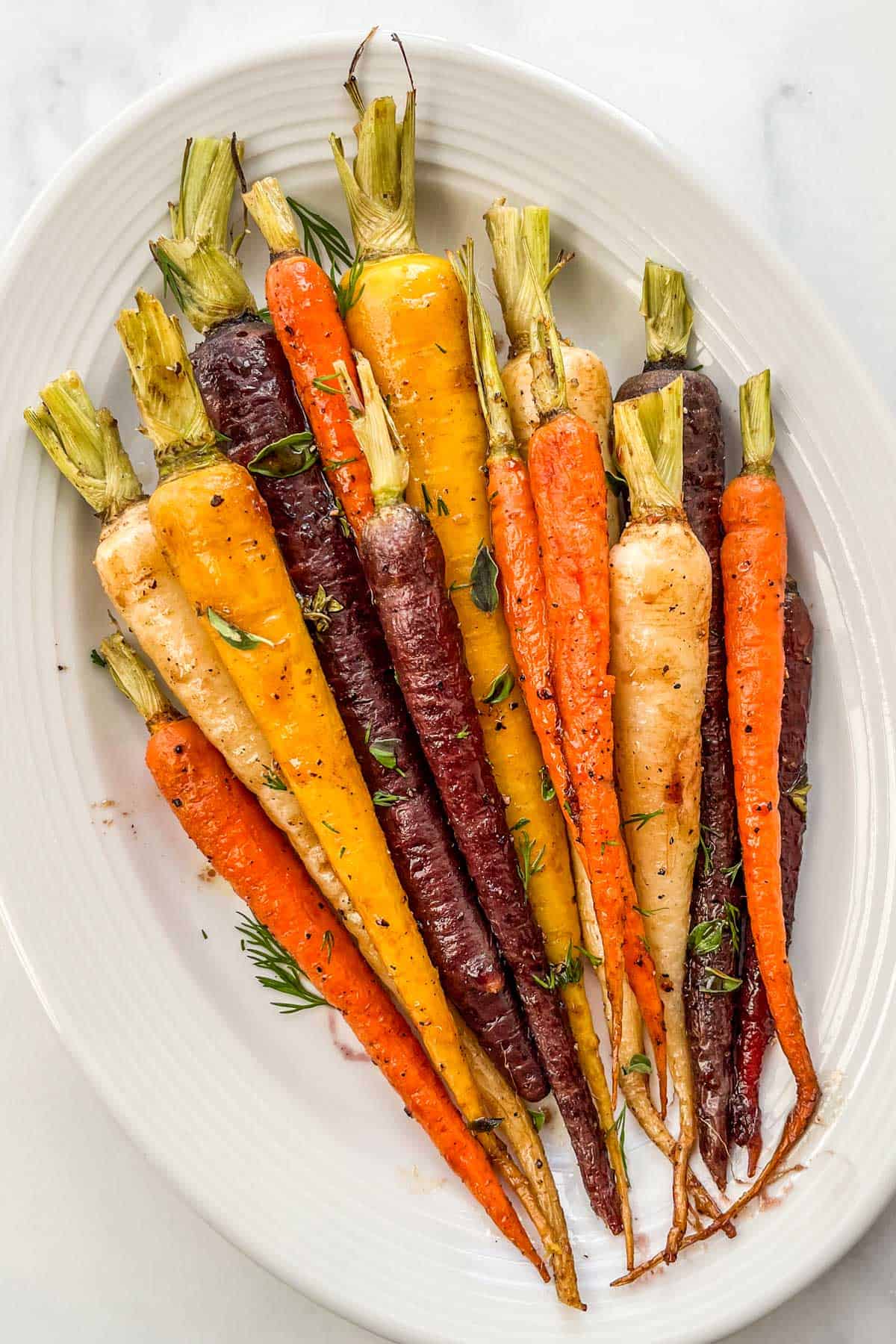 Honey roasted rainbow carrots on a white serving platter.