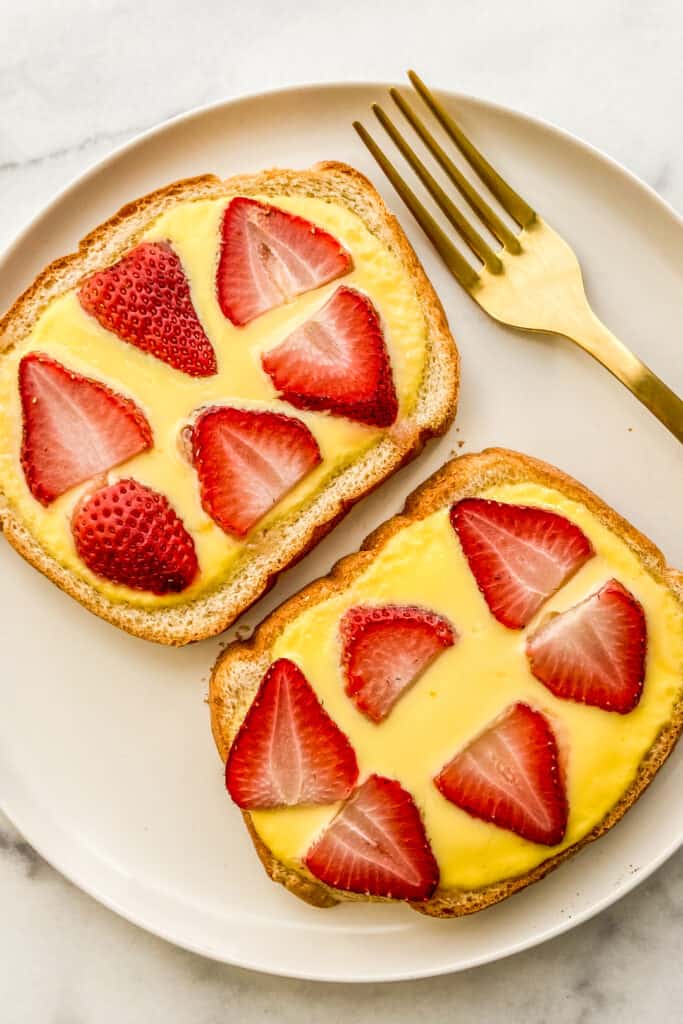 Yogurt toast topped with strawberries on a white plate.