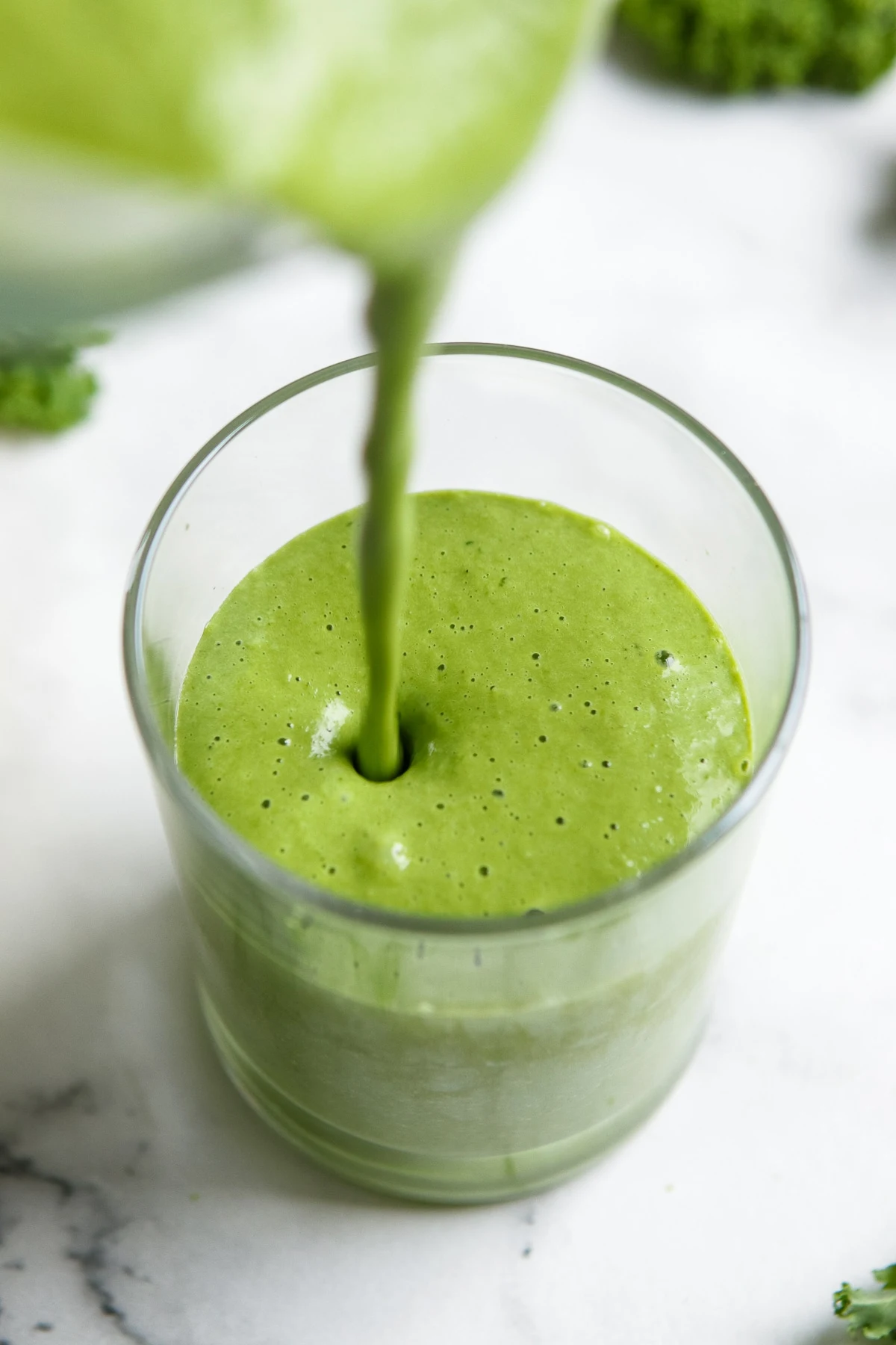 Kale smoothie being poured into a glass.