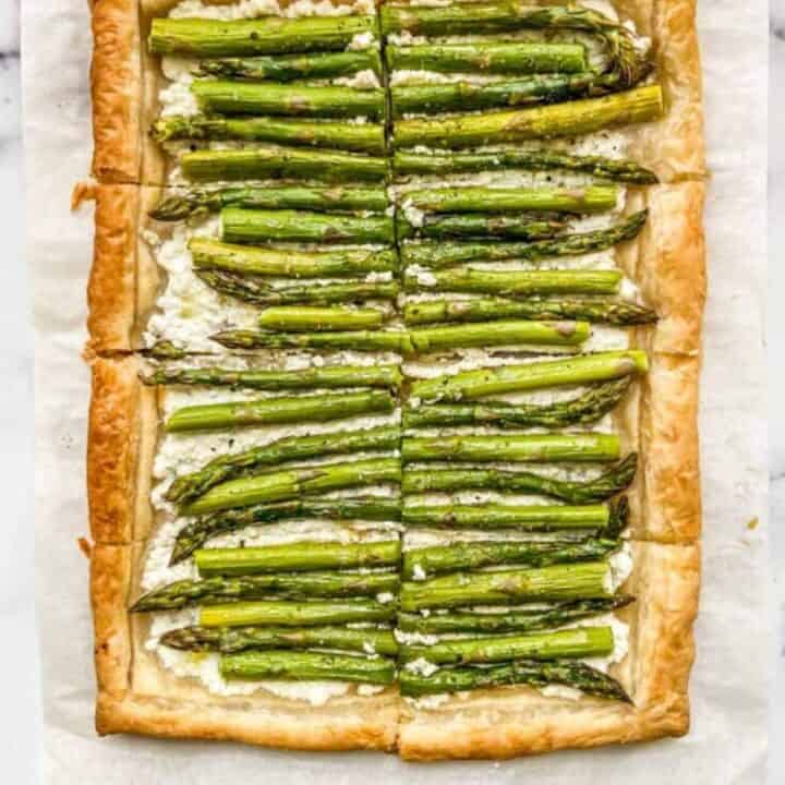 Asparagus puff pastry tart on parchment paper.