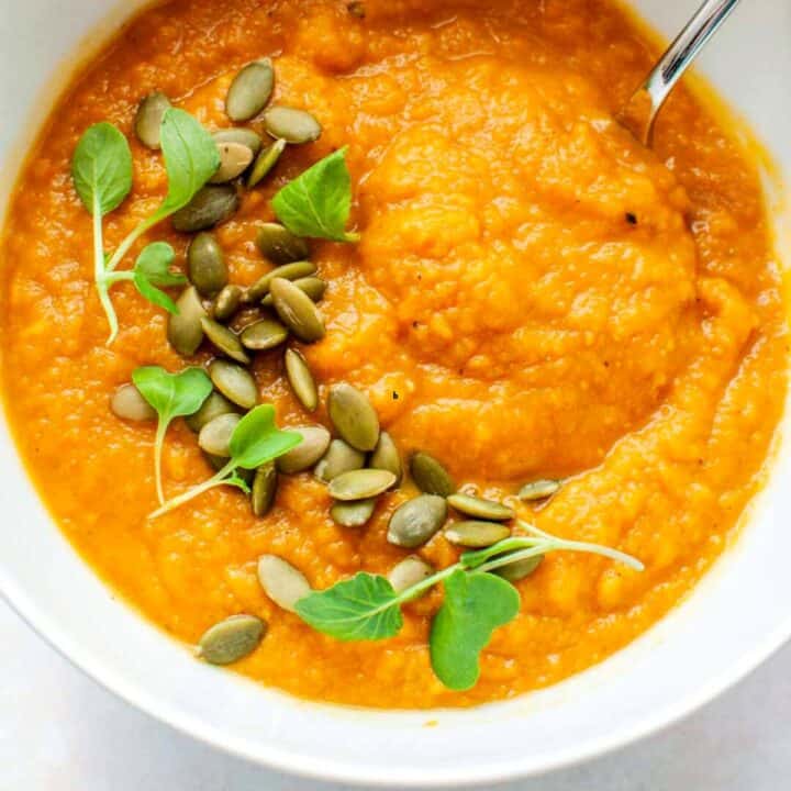 Butternut squash soup topped with pepitas in a white bowl.