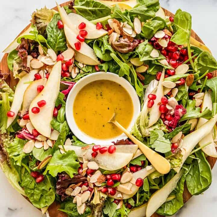 An edible wreath salad with greens and pomegranates.