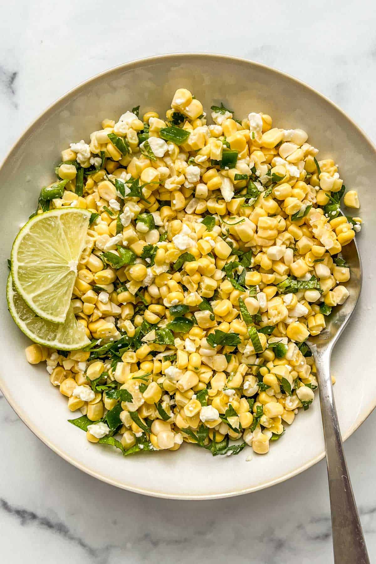 Corn feta salad in a serving bowl with a spoon.