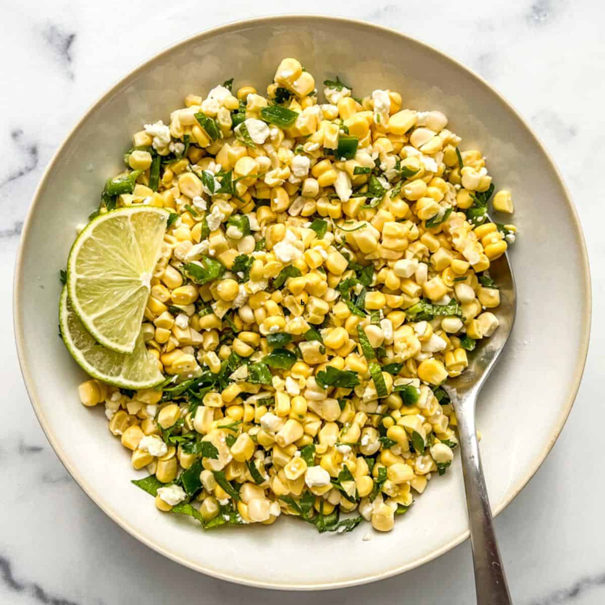 Corn and feta salad in a serving bowl with a spoon.