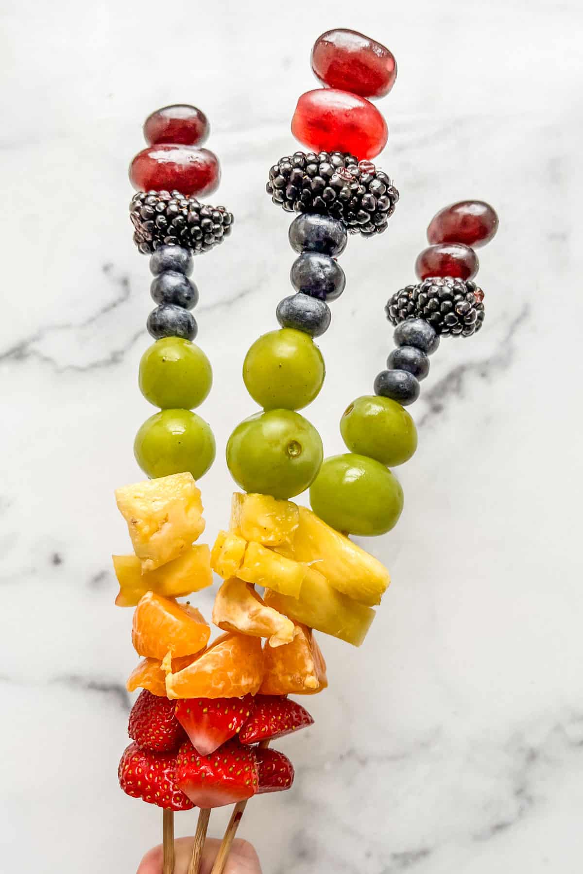 Three rainbow fruit skewers.