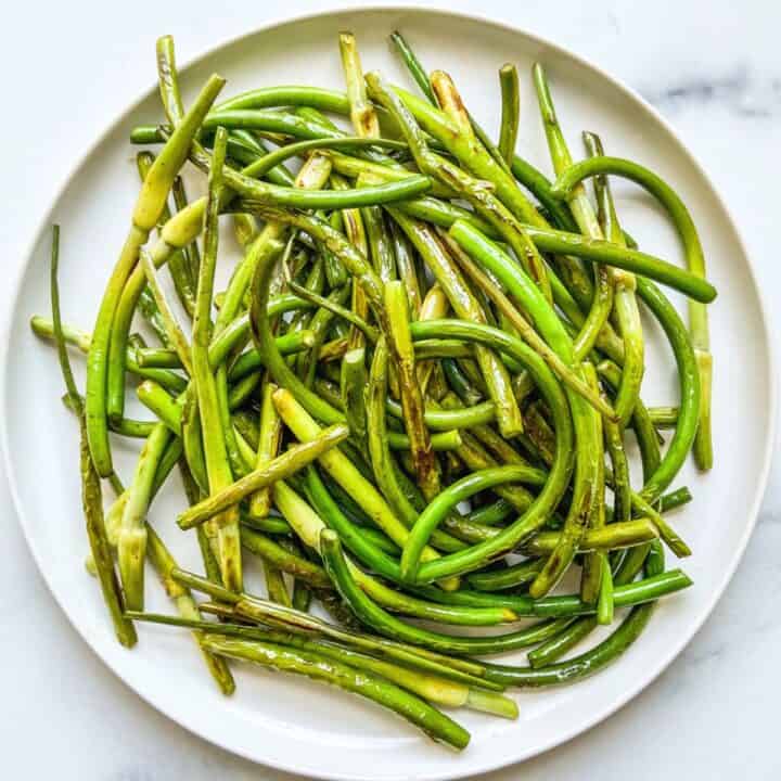 Sautéed garlic scapes on a white plate.