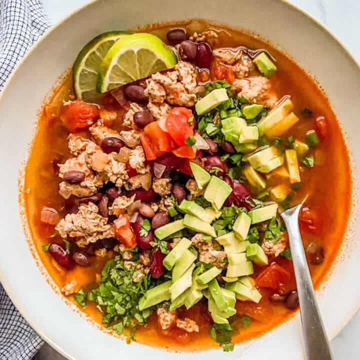 Ground chicken chili topped with avocados in a bowl.