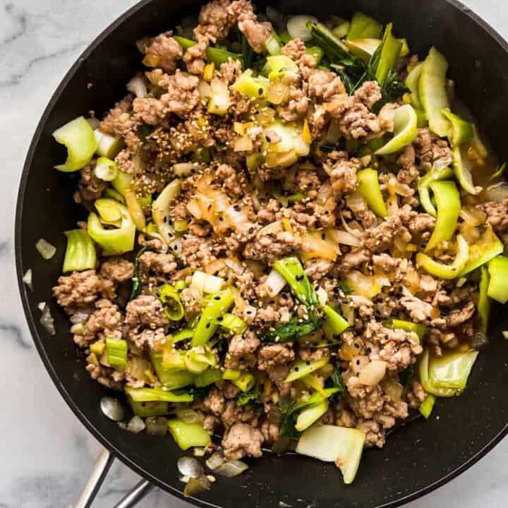 A ground pork and bok choy stir fry in a skillet.