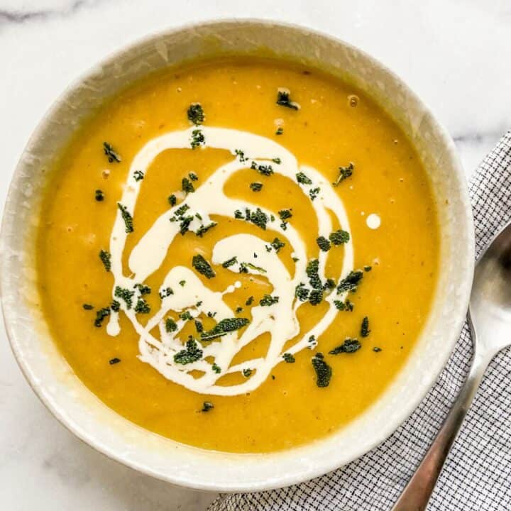 A bowl of roasted acorn squash soup with a cream swirl.