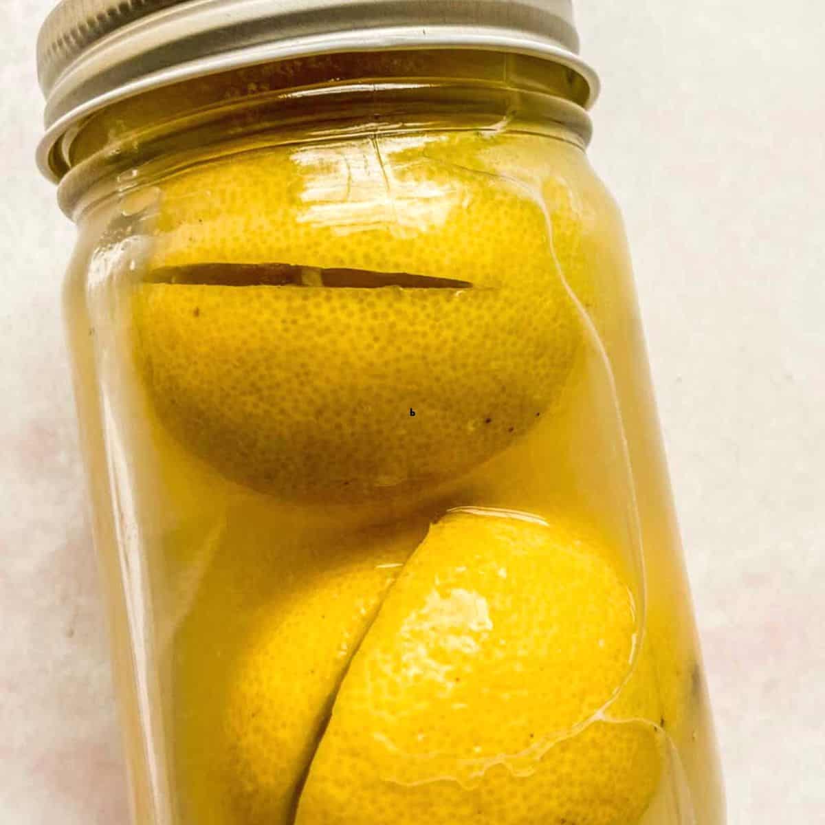 Two preserved lemons in a glass jar.