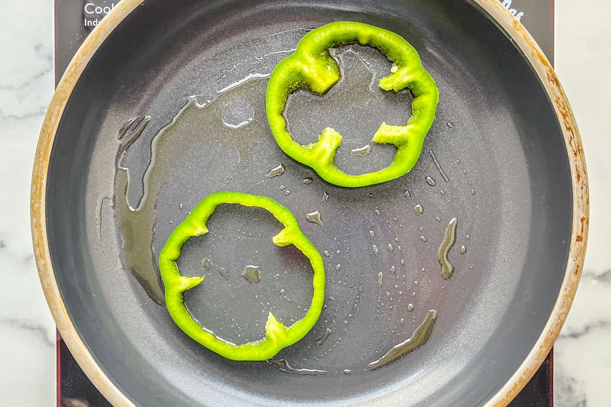 Slices of green pepper in a frying pan.