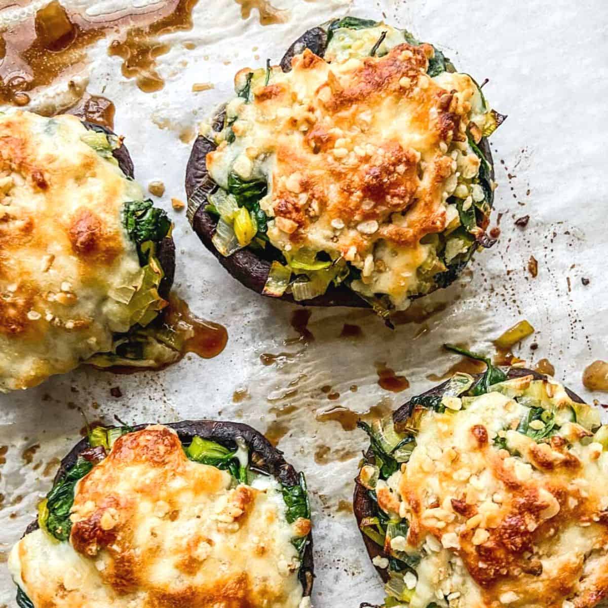 Four stuffed portobello mushrooms on parchment paper.