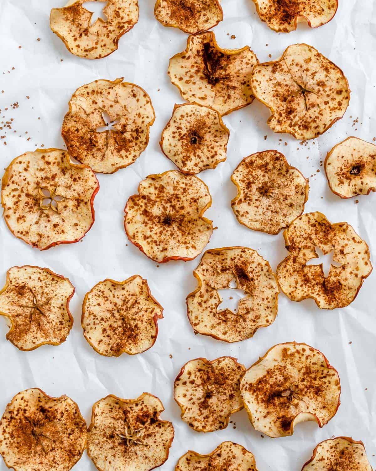 Baked apple chips on parchment paper.