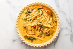 The filling for a breakfast quiche in an uncooked pie crust.