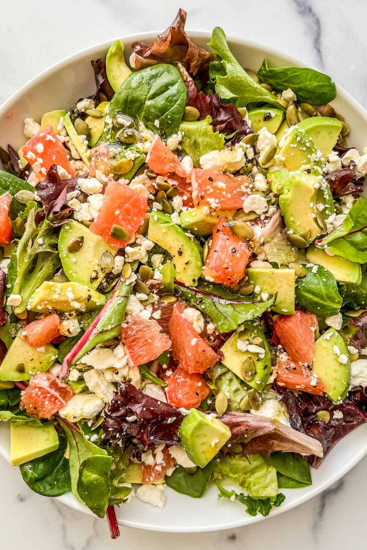 A grapefruit salad with avocado, feta, and pepitas in a bowl.