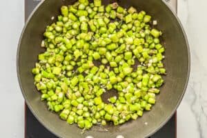 Asparagus and minced ginger cooking in a skillet.