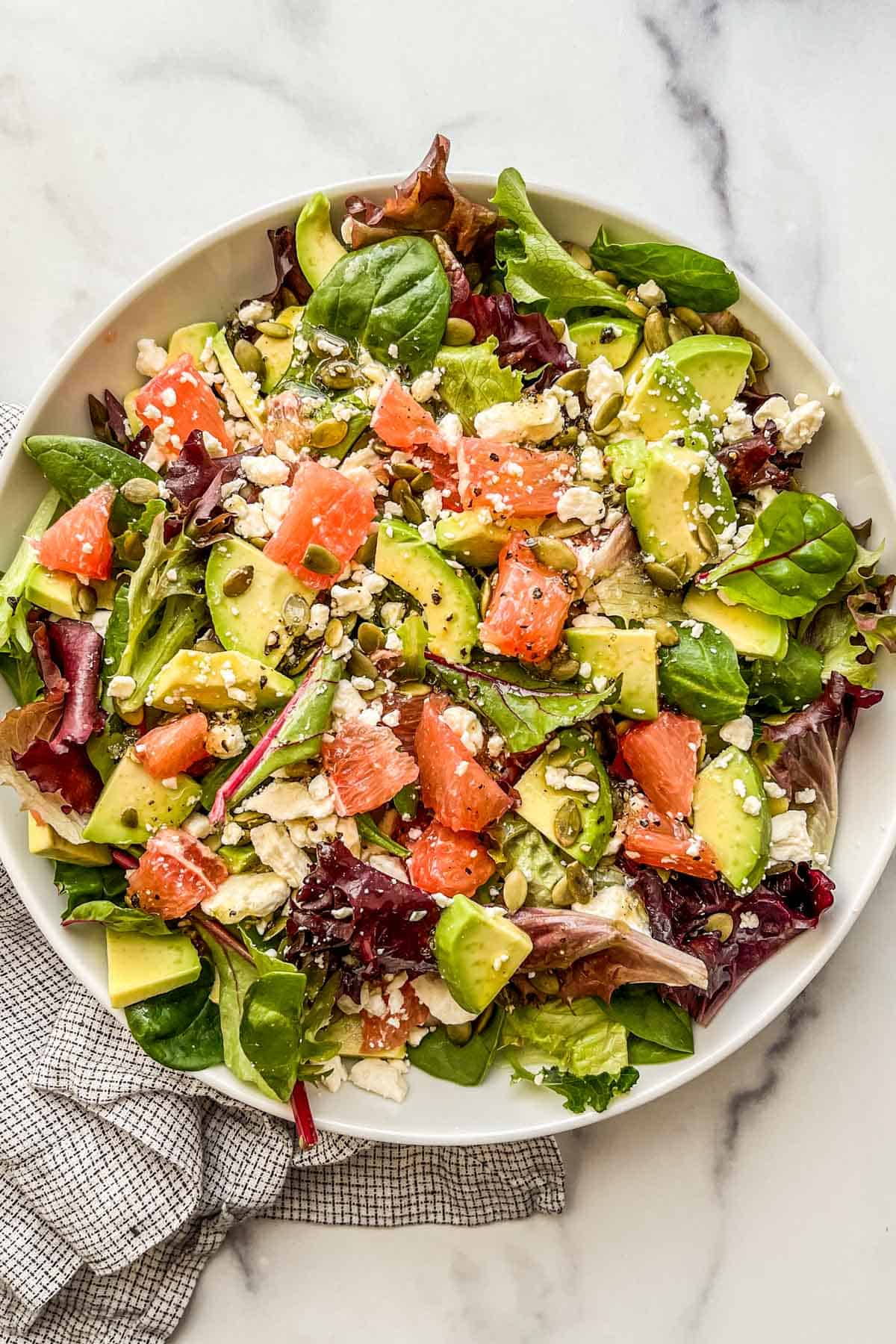 A grapefruit avocado salad in a white serving bowl.