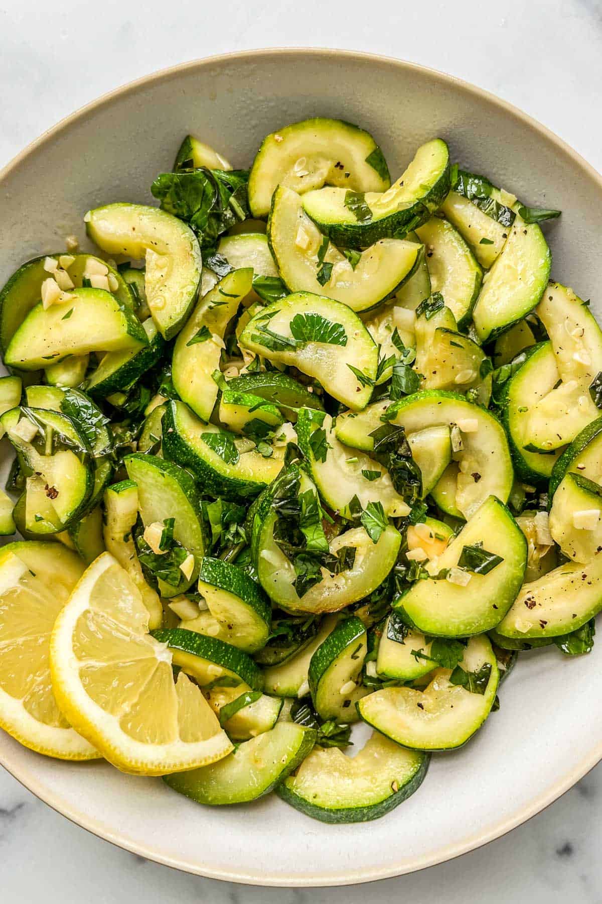 Cooked zucchini in a white serving bowl.