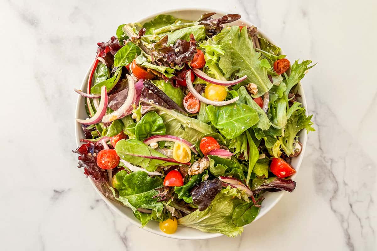 A spring mix salad in a white serving bowl.