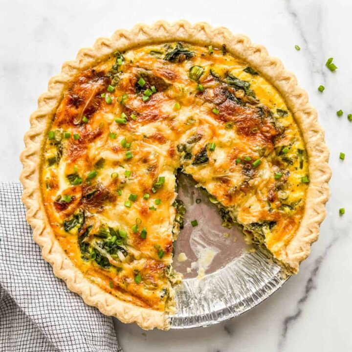 A vegetarian quiche with a slice cut out of it.