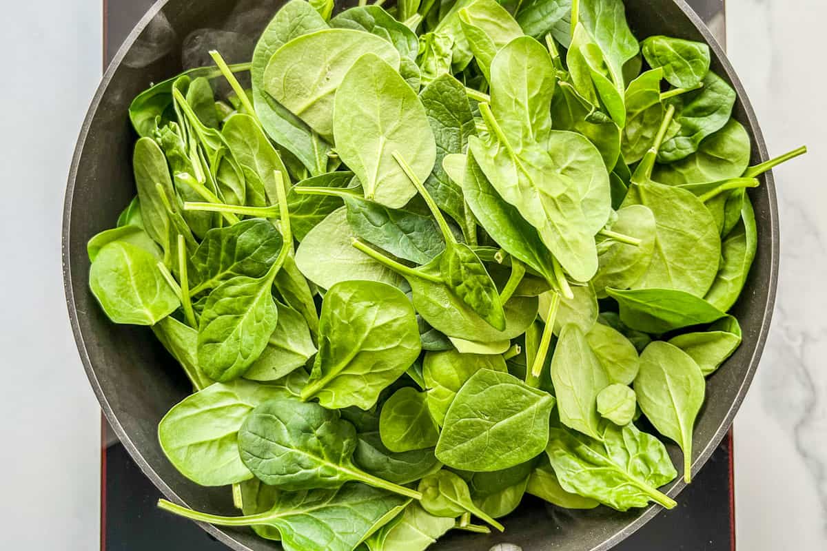 Spinach being wilted in a pan.