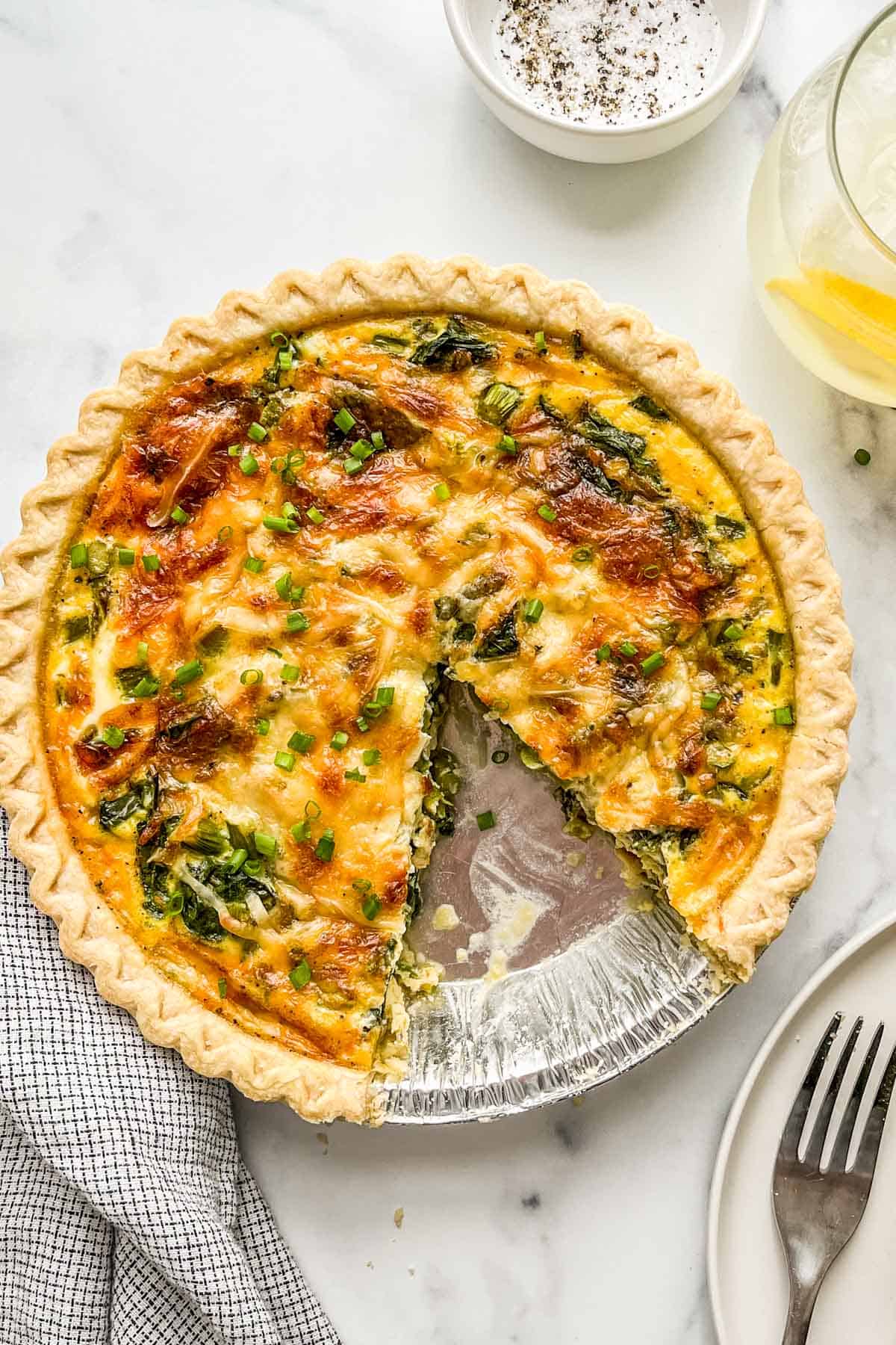 A vegetarian quiche with a slice cut out of it.