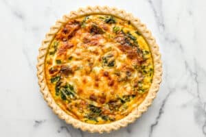 Cooked vegetarian quiche on a marble background.
