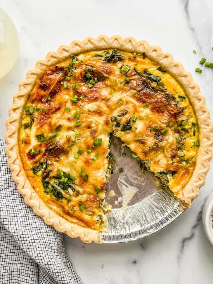 A vegetarian quiche with a slice cut out of it.