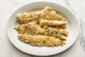Baked parmesan panko pollock fillets on a white serving tray.