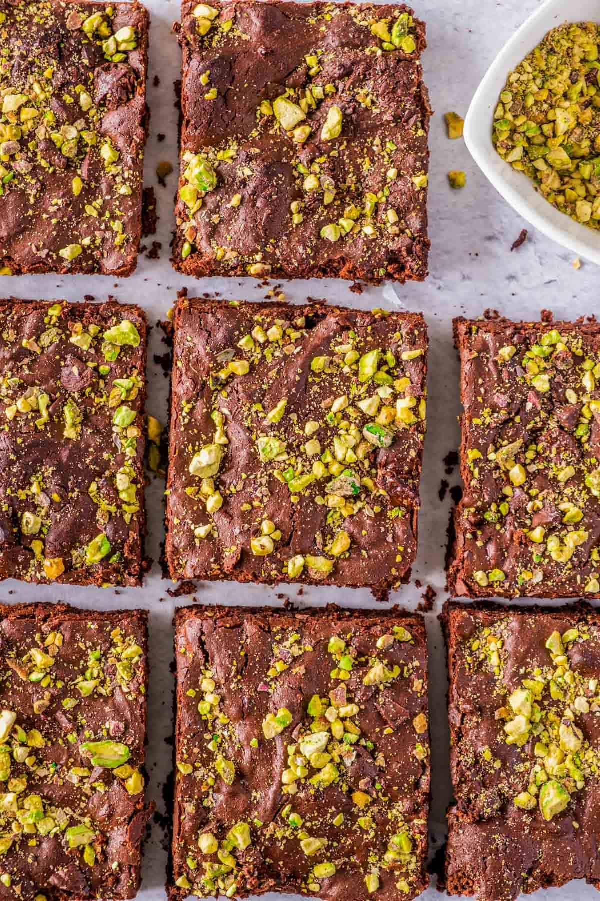 Several gluten free brownies topped with pistachios.