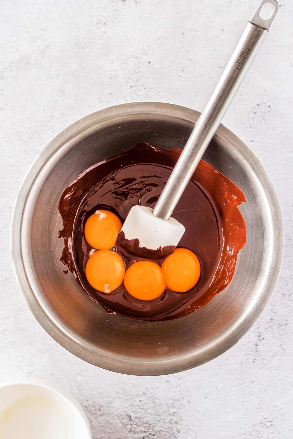 Melted chocolate and egg yolks in a mixing bowl.