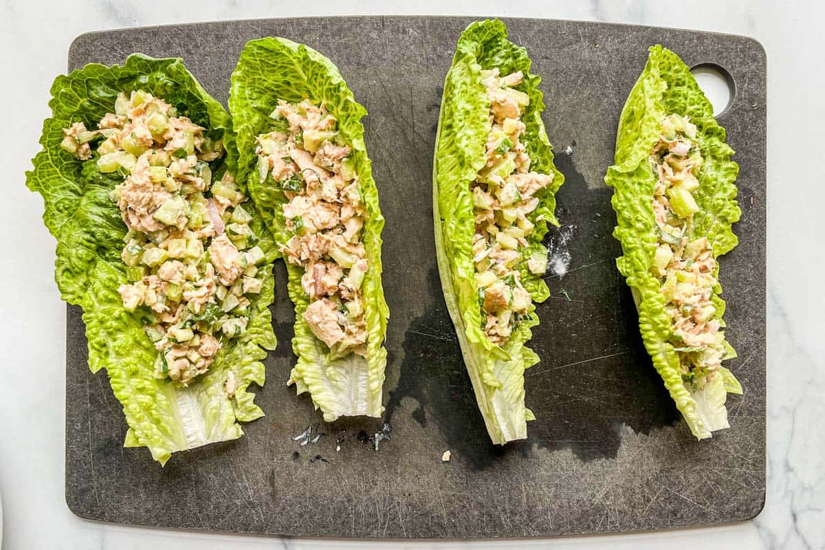 Four romaine lettuce wraps with tuna salad on a cutting board.