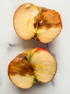 A halved apple with a large bruise spot.