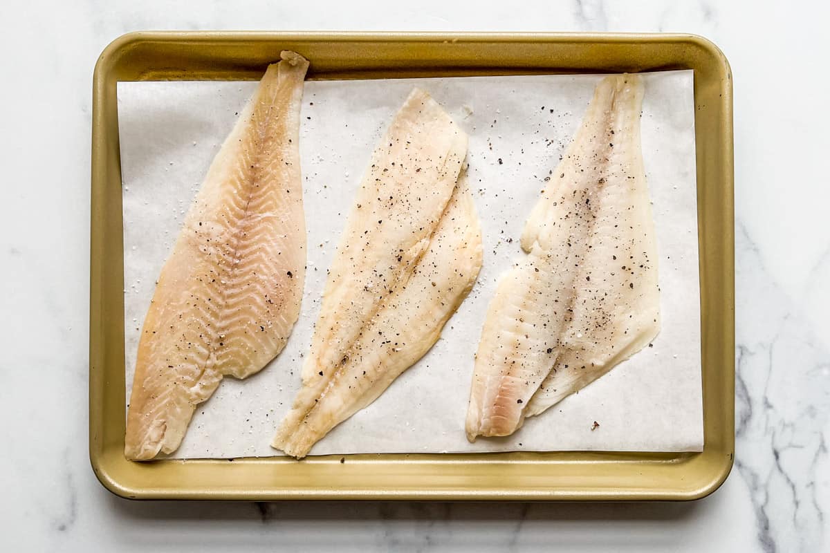 Sole fillets on a parchment lined baking sheet.