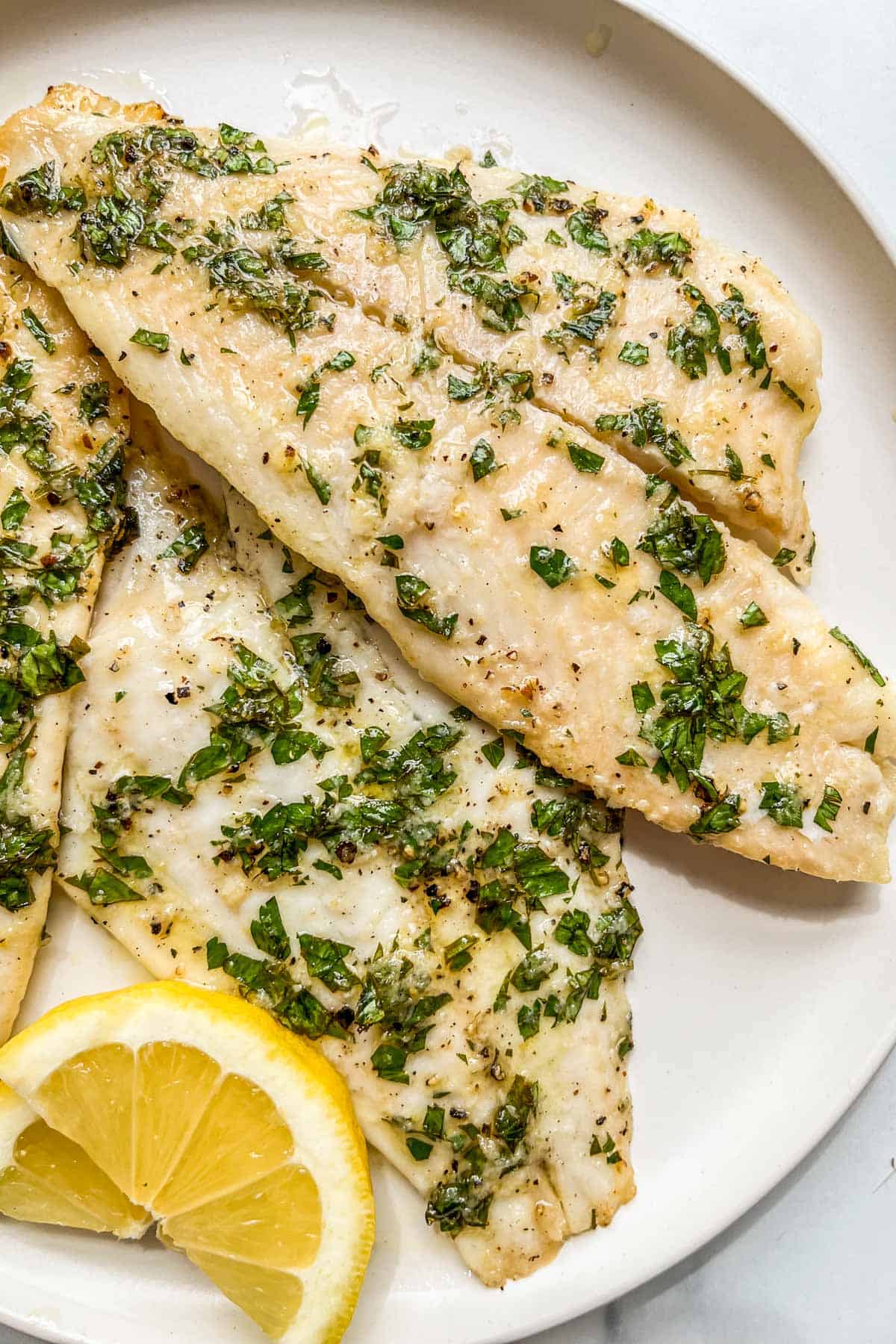 Baked lemon garlic sole fillets on a white plate.