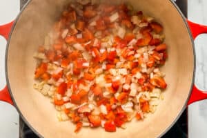 Diced bell pepper and onions cooking in a pot.