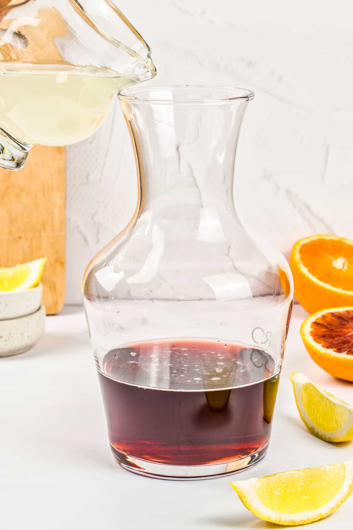 Lemon juice being poured into a pitcher of red wine.