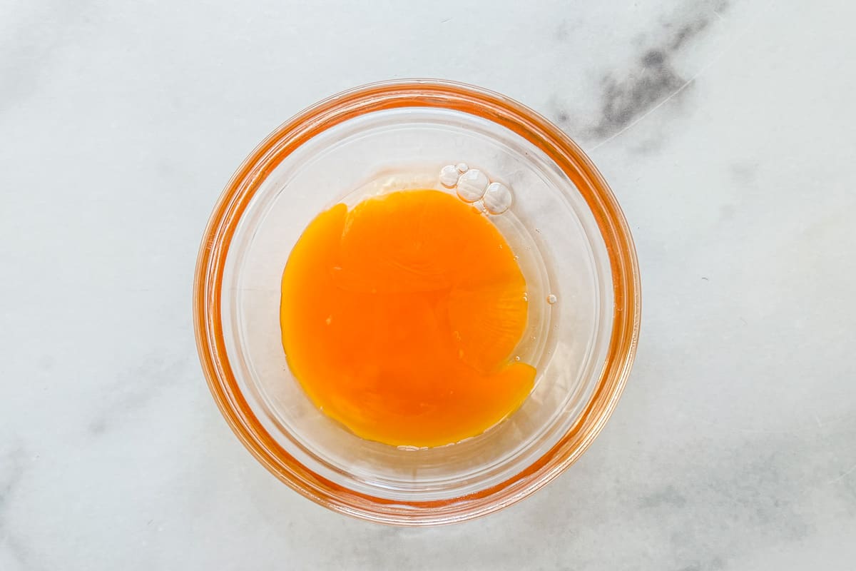 An egg yolk in a small glass bowl.