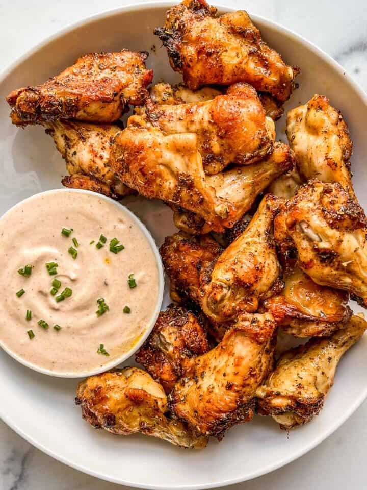 Baked chicken wings with a bowl of dipping sauce.