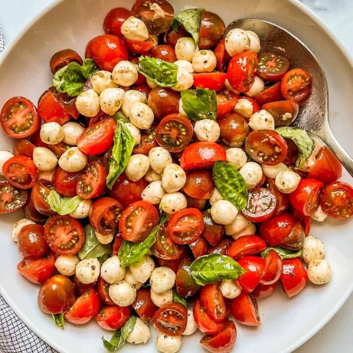 Cherry tomato caprese salad in a white dish.