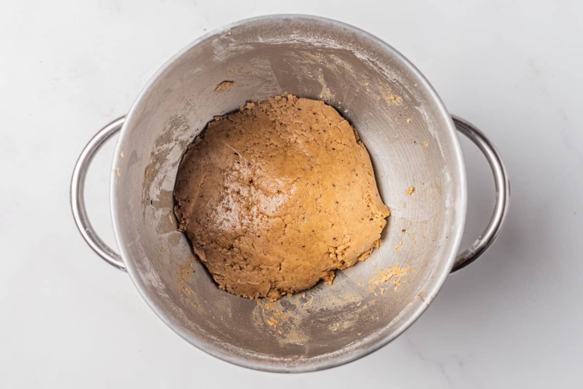 A metal bowl with a ball of gingerbread dough.