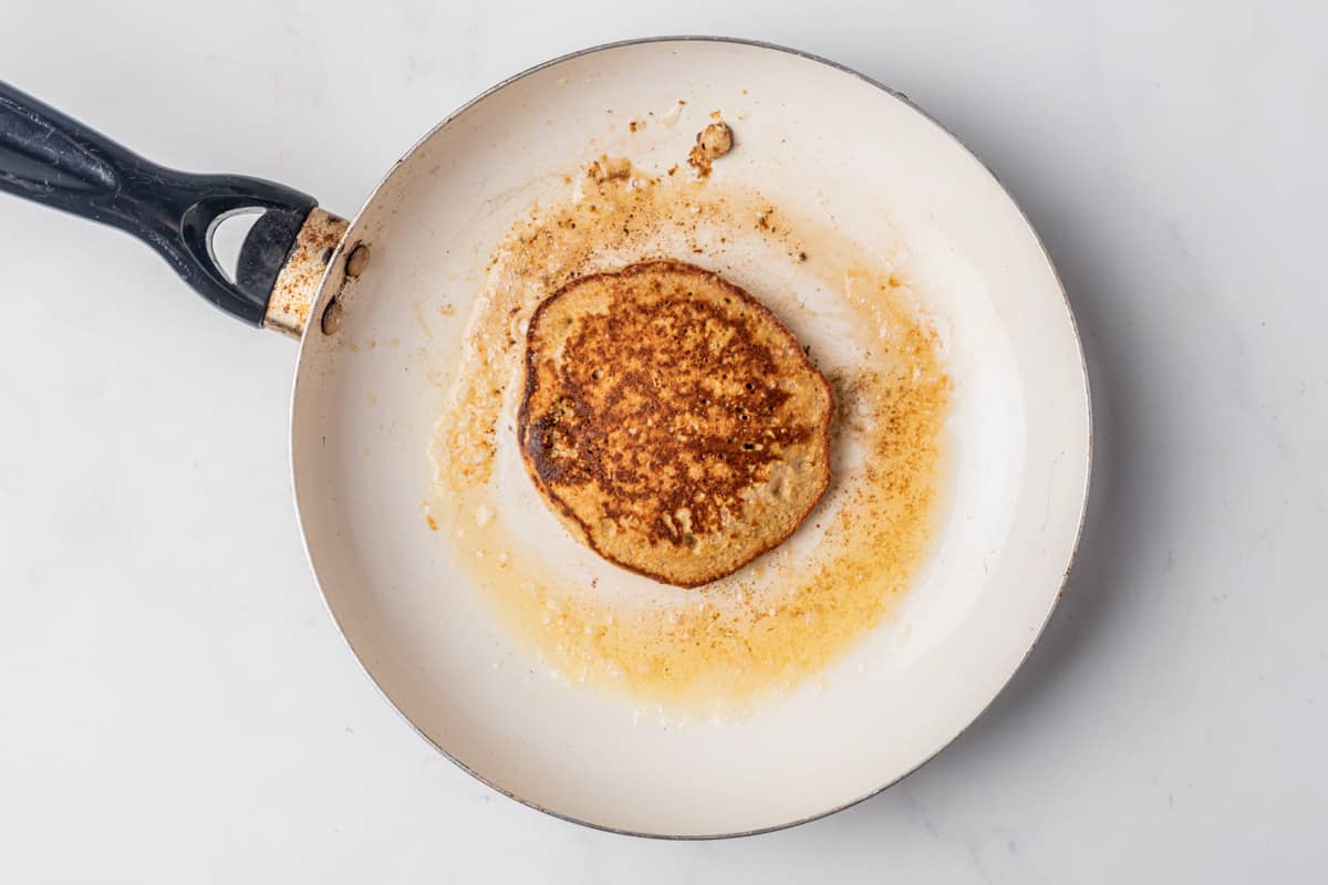 A banana oat pancake being cooked in a skillet.